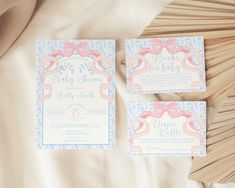 two pink and blue wedding cards sitting on top of a bed