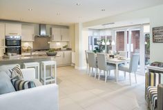 a kitchen and dining room area in a house with white tile flooring, beige walls and furniture