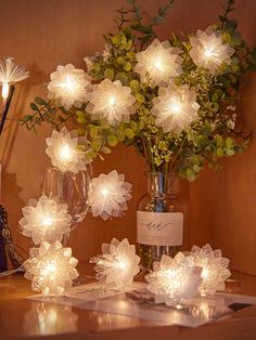 flowers and wine glasses on a table with lights in the shape of snowflakes