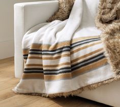 a white couch with a striped blanket on top of it next to a wooden floor