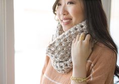 a woman wearing a knitted cowl around her neck and smiling at the camera