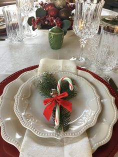 a christmas table setting with candy canes and greenery on the plate, silverware