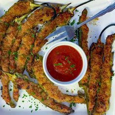 some fried food is on a white plate with sauce and tongs next to it