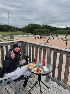 a woman sitting at a table on top of a wooden deck with a plate of food in front of her