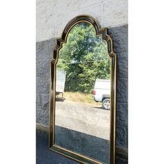 a large mirror sitting on the side of a wall next to a truck and trees