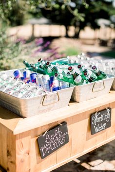 several bottles of beer are lined up on a wooden table in front of some bushes