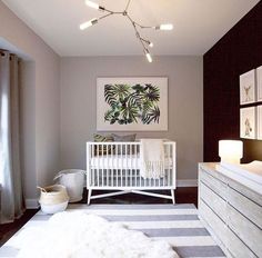 a baby's room with a white crib, dresser and large painting on the wall