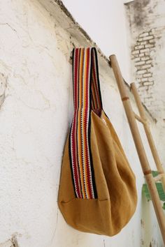 a brown bag hanging on the side of a white wall next to a bamboo stick