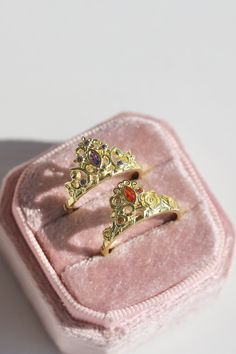 two rings sitting on top of a pink velvet box