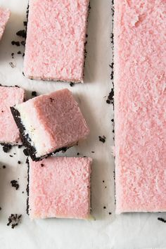 several pieces of pink cake sitting on top of a white counter next to each other