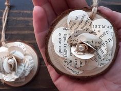 a hand holding an ornament made out of book pages with a flower on it