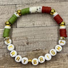 a bracelet that says happy on it with gold beads and green, white and red cords