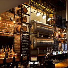 a bar with lots of wooden barrels hanging from it's wall and shelves filled with liquor