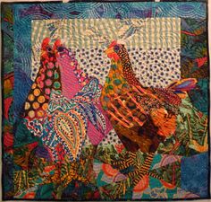 two chickens are standing next to each other on a patchwork quilted wall hanging