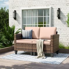 a couch sitting on top of a wooden floor next to a white brick building with windows