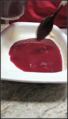 a spoon is being used to dip something in a bowl with red sauce on it