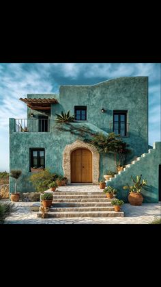 an adobe style house with steps leading up to the front door and stairs leading up to the second floor