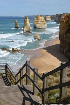 stairs lead down to the beach with large rock formations in the water and sand on either side