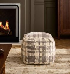 a living room with a fire place in the fireplace and a checkered footstool