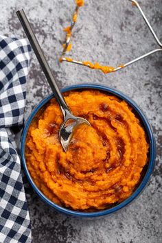 a blue bowl filled with sweet potato mashed potatoes and a spoon resting on top