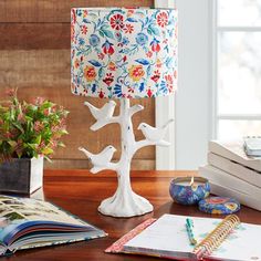 a lamp that is sitting on top of a table next to some books and flowers