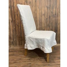 a chair with a white cover on it in front of a wood paneled wall