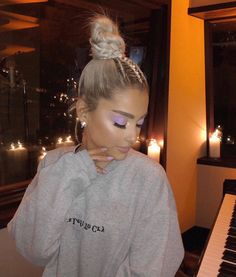 a woman with purple eyeshades and braids on her head sitting in front of a piano