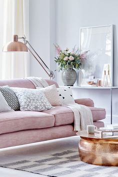 a living room filled with pink couches and pillows on top of a white rug