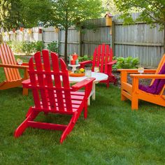 colorful chairs and tables in the grass near a wooden fence with a purple towel on it