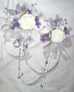 two white and purple bridal bouquets sitting on top of a bed next to each other