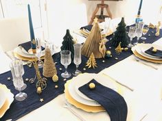 the table is set for christmas dinner with blue linens and gold placemats