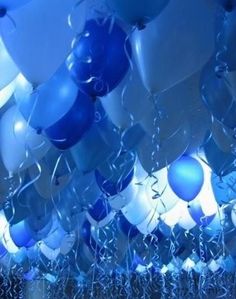 many blue and white balloons are floating in the air with streamers all around them