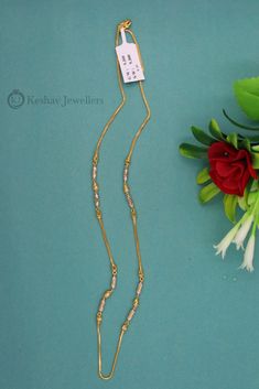 a necklace with a tag on it next to flowers