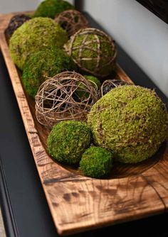 moss covered balls are sitting on a wooden platter