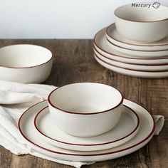 a table topped with white dishes and plates on top of a wooden tablecloth covered table