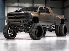 a brown truck with big tires in a garage area, on display at an automobile show