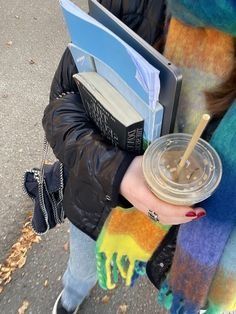 a person holding a book and drink in their hand