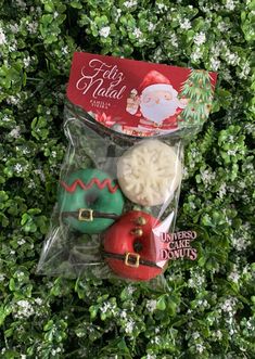 an assortment of christmas cookies in a plastic bag on top of some bushes with white flowers