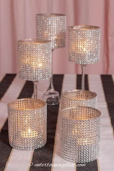 four crystal candle holders sitting on top of a black and white striped tablecloth covered table