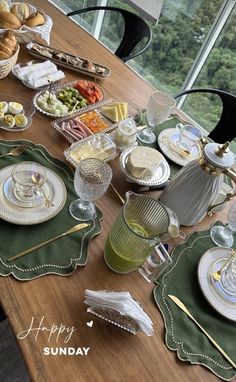 a wooden table topped with plates and bowls filled with food next to a large window