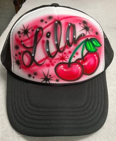 a trucker hat with the word lil on it and two cherries painted on it