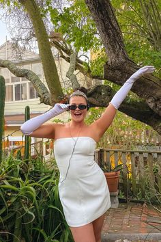 a woman in a white dress and headphones posing for the camera with her arms outstretched