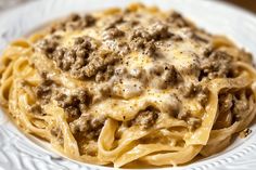 a white plate topped with pasta covered in meat and cheese sauce on top of it