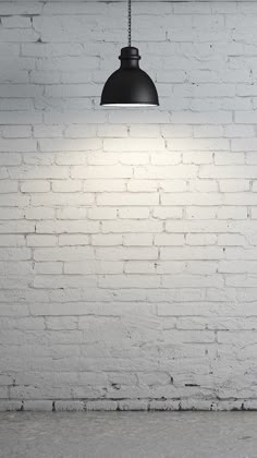 a white brick wall with a black light hanging from it's side and an empty floor below