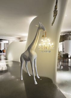 a white giraffe standing next to a chandelier