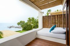 a bed sitting on top of a wooden floor next to a lush green hillside near the ocean