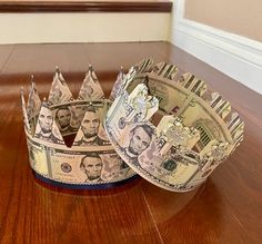 two crowns made out of money sitting on top of a wooden floor