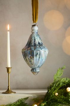 an ornament hanging from a christmas tree next to a candle