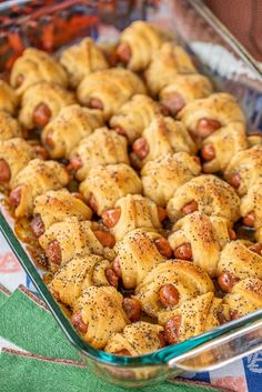 hot dogs wrapped in crescented bread and sprinkled with seasoning sit in a casserole dish