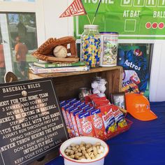 a table topped with lots of food and baseball related items next to a chalkboard sign